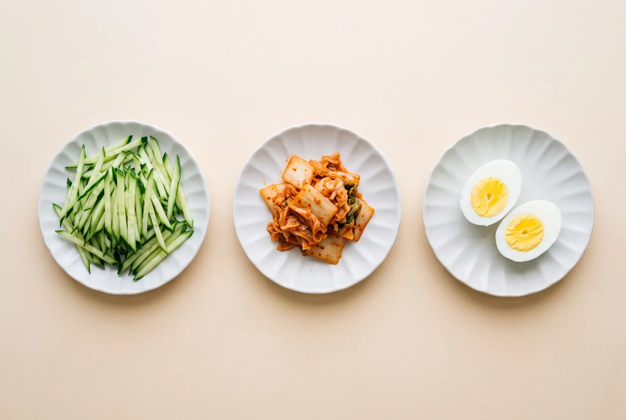 접시에 나눠 담은 오이채, 잘게 썬 김치, 반으로 가른 삶은 달걀