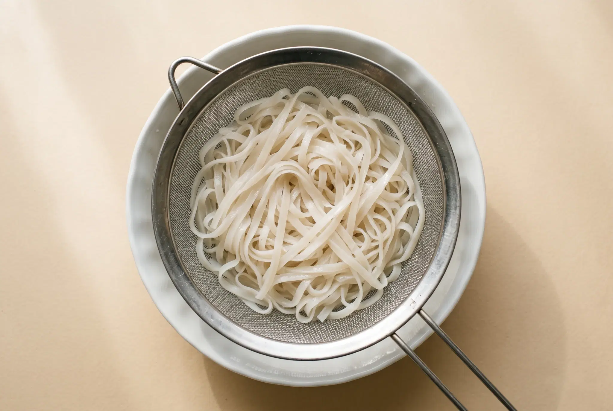 데친 뒤 찬물에 헹궈 체에 밭쳐 둔 납작한 생쌀국수